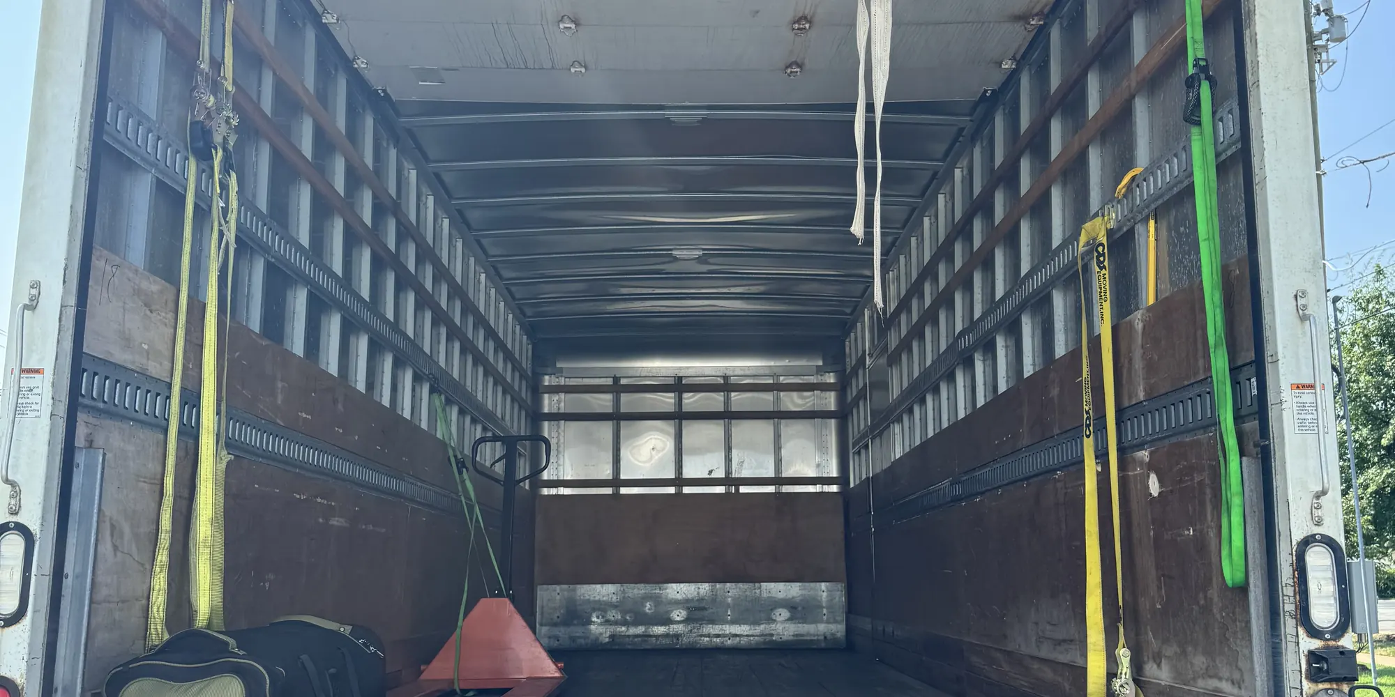 Clean box truck interior with load straps and pallet jack, ready to load