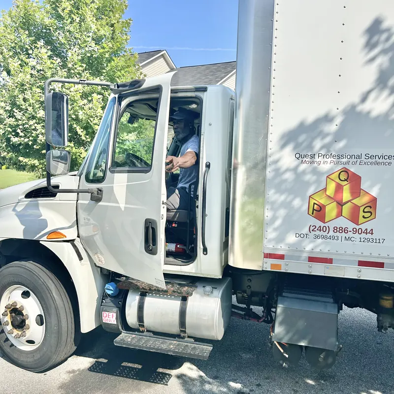 Quest driver in a branded box truck showing the company DOT and MC numbers