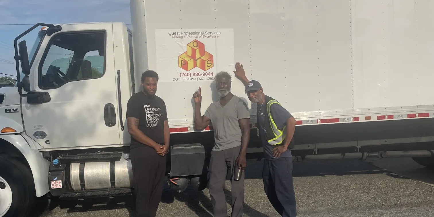 Three Quest crew members beside a branded Quest box truck