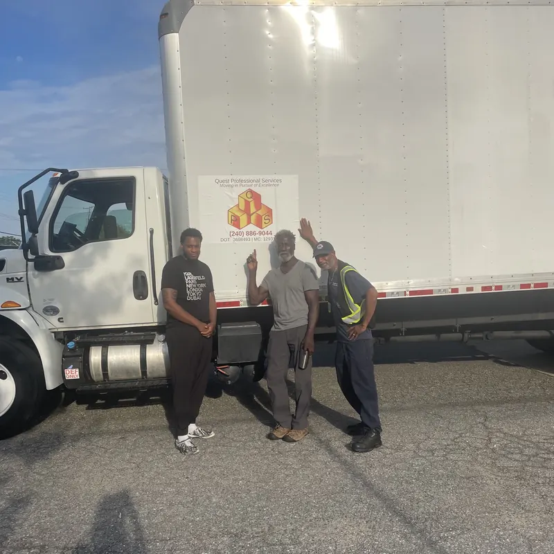 Quest crew members beside a branded box truck